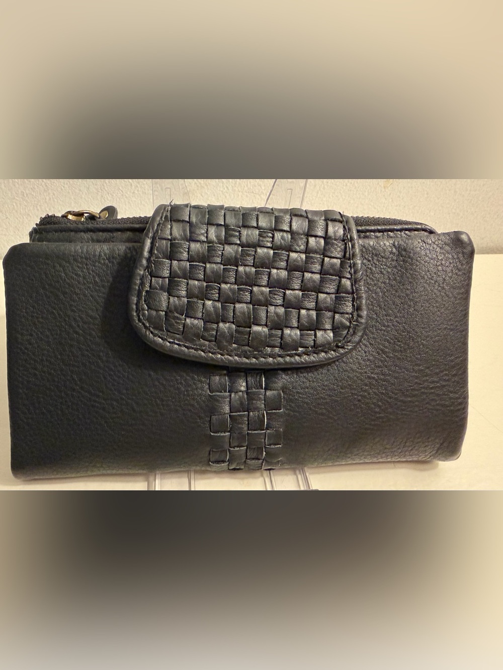 Leather wallet in black with woven flap closure.
